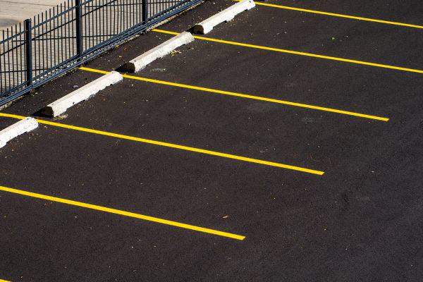 Commercial Car Park With New Asphalt Yellow Lane Markings And Black Fence